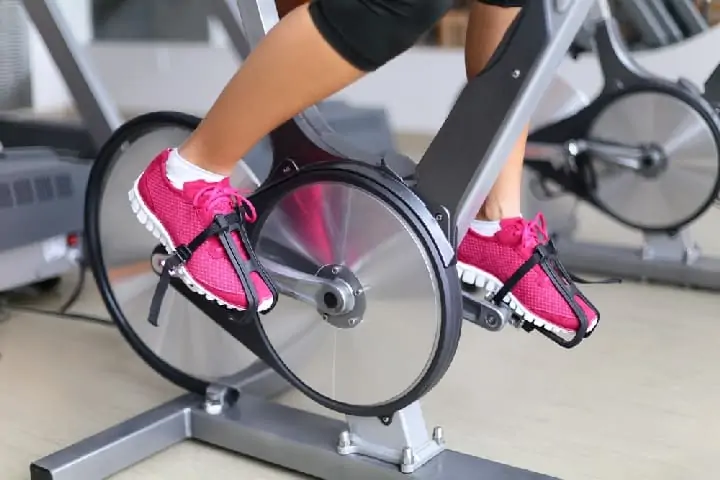 Exercise bike with spinning wheels - woman biking
